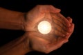 Hands holding and protecting lit or burning candle candlelight on darkness. Royalty Free Stock Photo