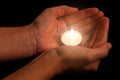 Hands holding and protecting lit or burning candle candlelight on darkness. Royalty Free Stock Photo