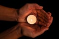 Hands holding and protecting lit or burning candle candlelight on darkness. Royalty Free Stock Photo