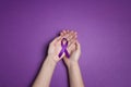 Hands holding Purple ribbons on a purple background. World epilepsy day