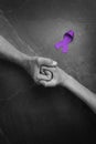 Hands holding purple ribbons top view