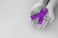 Hands holding purple or violet ribbon on purple background with copy space. Pancreatic Cancer Testicular Cancer Awareness Cancer Royalty Free Stock Photo