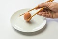Hands holding raw egg on a plate with chopsticks isolated on white background Royalty Free Stock Photo