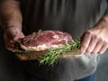 Hands holding raw uncooked duck breast with rosemary and thyme on cutting board. Royalty Free Stock Photo