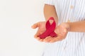 Hands holding Red burgundy ribbon bow on white background with copy space, symbol of Multiple Myeloma or Plasma cell cancer Royalty Free Stock Photo