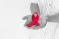 Hands holding Red burgundy ribbon bow on white background with copy space, symbol of Multiple Myeloma or Plasma cell cancer Royalty Free Stock Photo