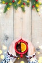 Hands holding red ceramic cup with mulled wine, wooden background with copy space