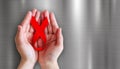 Hands holding red ribbon on metal background for world aids day