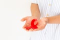 Hands holding red ribbon on white background copy space, symbol for the solidarity of people living with HIV/AIDS, and for the Royalty Free Stock Photo