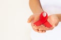 Hands holding red ribbon on white background copy space, symbol for the solidarity of people living with HIV/AIDS, and for the Royalty Free Stock Photo