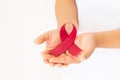 Hands holding red ribbon on white fabric with copy space, symbol for the solidarity of people living with HIV/AIDS, and for the Royalty Free Stock Photo