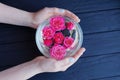 Hands holding a round glass vase with buds of red roses Royalty Free Stock Photo