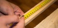 Male hands using a roulette and pencil making a mark on wooden plank Royalty Free Stock Photo