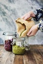 Hands holding sack and pouring beans to the glass jar