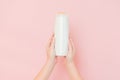 Hands holding shampoo, hair conditioner or body lotion bottle in pink background. Cosmetics bottle Royalty Free Stock Photo