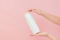 Hands holding shampoo, hair conditioner or body lotion bottle in pink background. Cosmetics bottle Royalty Free Stock Photo