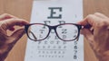 Hands holding sight glasses in front of optician sight chart. Eyesight optician concept Royalty Free Stock Photo