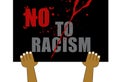 Hands holding sign board saying No To Racism and stains of blood on black background Royalty Free Stock Photo