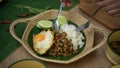 Hands holding silverware eating Stir fried minced pork with basil Pad ka prao, rice fried egg serving on wicker plate Royalty Free Stock Photo