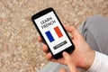 Hands holding smart phone with learn French concept on screen Royalty Free Stock Photo