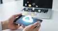 Hands holding smartphone with cloud computing icon and data transfer to laptop Royalty Free Stock Photo