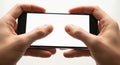Hands holding a smartphone horizontally playing a game or browsing with a blank white screen Royalty Free Stock Photo
