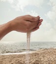 Hands holding and spilling sand with beach in the background Royalty Free Stock Photo