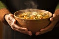 hands holding a steaming bowl of gumbo