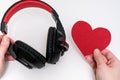 Hands holding stereo headphones and a red heart as a love music concept