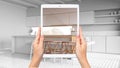 Hands holding tablet showing modern white kitchen, total blank project background, augmented reality concept, application to Royalty Free Stock Photo
