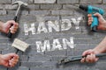Hands holding tools on grey brickwall background with text handyman on it Royalty Free Stock Photo