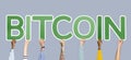 Hands holding up green letters forming the word bitcoin