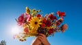 Hands holding a vibrant bouquet of wildflowers on a bright blue sky background. Generative AI Royalty Free Stock Photo