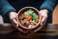 hands holding a warm pozole serving in rustic bowl