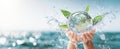 The hands holding a water globe surrounded by splashing leaves and purity..AI generated image Royalty Free Stock Photo