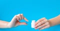 Hands holding white bottle for pills and pills on a blue background Royalty Free Stock Photo