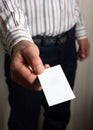 Hands holding a white business visit card, gift, ticket, pass, present close up on blurred blue background. Copy space Royalty Free Stock Photo