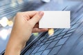 Hands holding a white business visit id card, gift, ticket, pass, present showing close up on blurred blue background Royalty Free Stock Photo