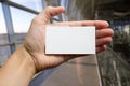 Hands holding a white business visit id card, gift, ticket, pass, present showing close up on blurred blue background Royalty Free Stock Photo