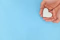 Hands holding a white heart in blue background. Kindness and pure love concept. Royalty Free Stock Photo