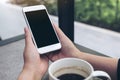 Hands holding white mobile phone with blank black desktop screen with coffee cup on table in cafe Royalty Free Stock Photo