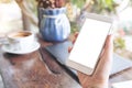 Hands holding white mobile phone with blank desktop screen with laptop and coffee cup on table in cafe Royalty Free Stock Photo