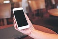 Hands holding white mobile phone with blank desktop screen with laptop computer on the table Royalty Free Stock Photo