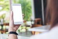 Hands holding white mobile phone with blank white screen in modern cafe Royalty Free Stock Photo