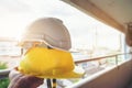 Hands holding a white and yellow helmet with a building under construction are blurred backgrounds Royalty Free Stock Photo
