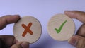 Hands Holding Wooden Circles with Check Mark and X Mark Symbolizing Right, Wrong, and Decision Making Royalty Free Stock Photo