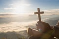 Hands holding wooden cross over open holy bible on the mountain background with morning sunrise, spirtuality and religion, Royalty Free Stock Photo
