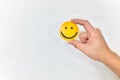 Hands holding a yellow smiley face on white background. Be positive and share happiness concept