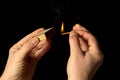 Hands holds a burning match on a black background. A wooden match burns in the hands of a macro. Igniting a match on a box. Smoke Royalty Free Stock Photo