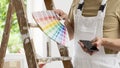 Hands of house painter man decorator choose the color using the sample swatch, work of the house to renovate, use mobile phone, a